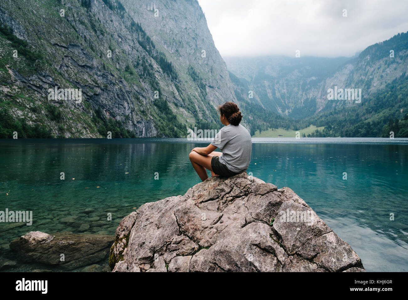 Girl sitting on rock looking at beautiful and misty lake in the Stock ...