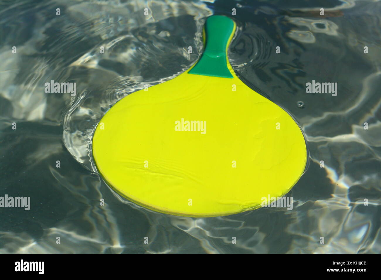 A yellow toy racket floating on the water, to play beach ball games Stock Photo Alamy