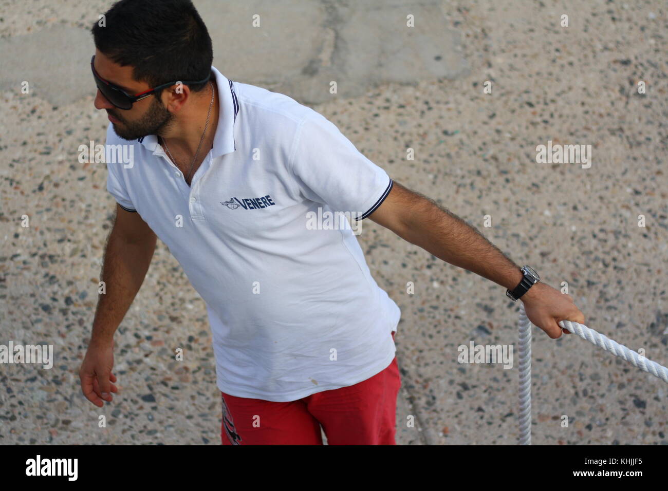 A seaman securing a boat with a thick rope in the port Stock Photo - Alamy