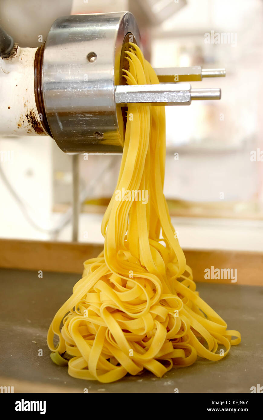 Fresh home-made pasta tagliatelle coming out of pasta machine Stock Photo