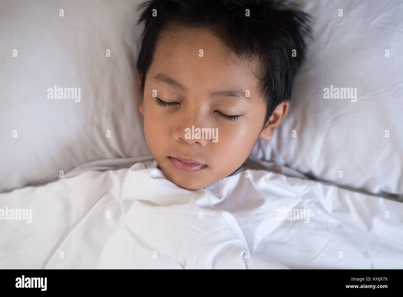 boy sleeping on bed with white sheet and pillow.asian kid fall asleep