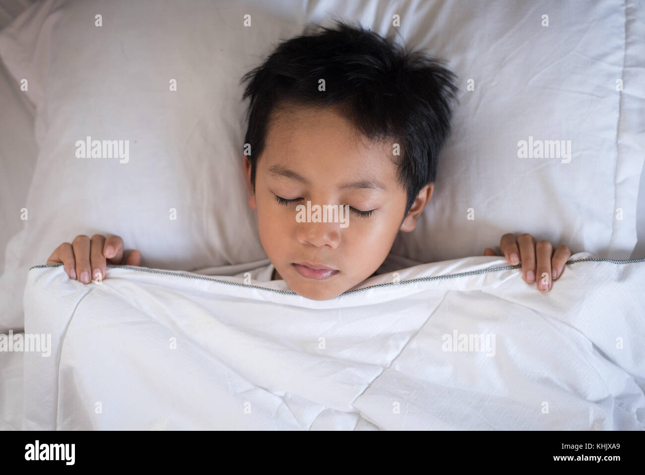boy sleeping on bed with white sheet and pillow.asian kid fall asleep