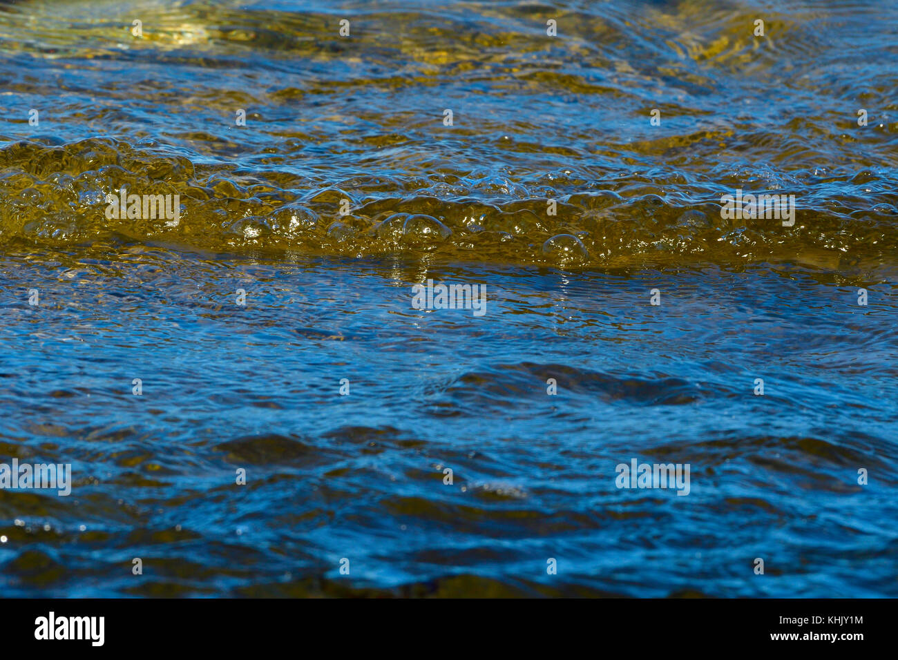 A close up image of some ocean waves rippling into shore creating some bubbles on Vancouver Island British Columbia Canada. Stock Photo