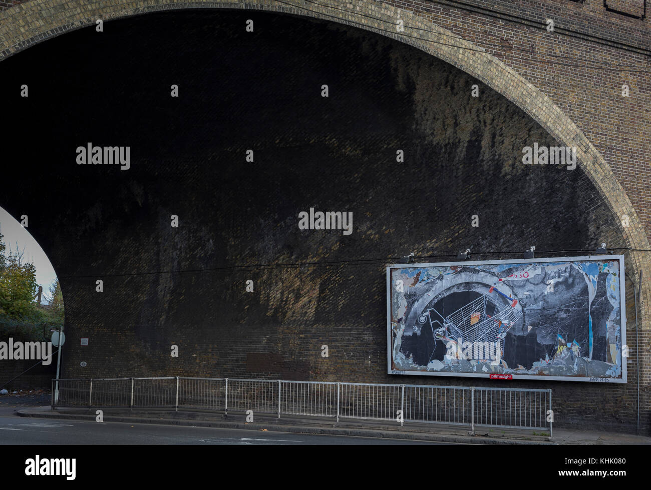 A billboard featuring a a supermarket trolley falling into a drain located beneath the arch of a Victorian-era railway bridge over the road in Peckham, on 16th November 2017, in south London, England. Stock Photo