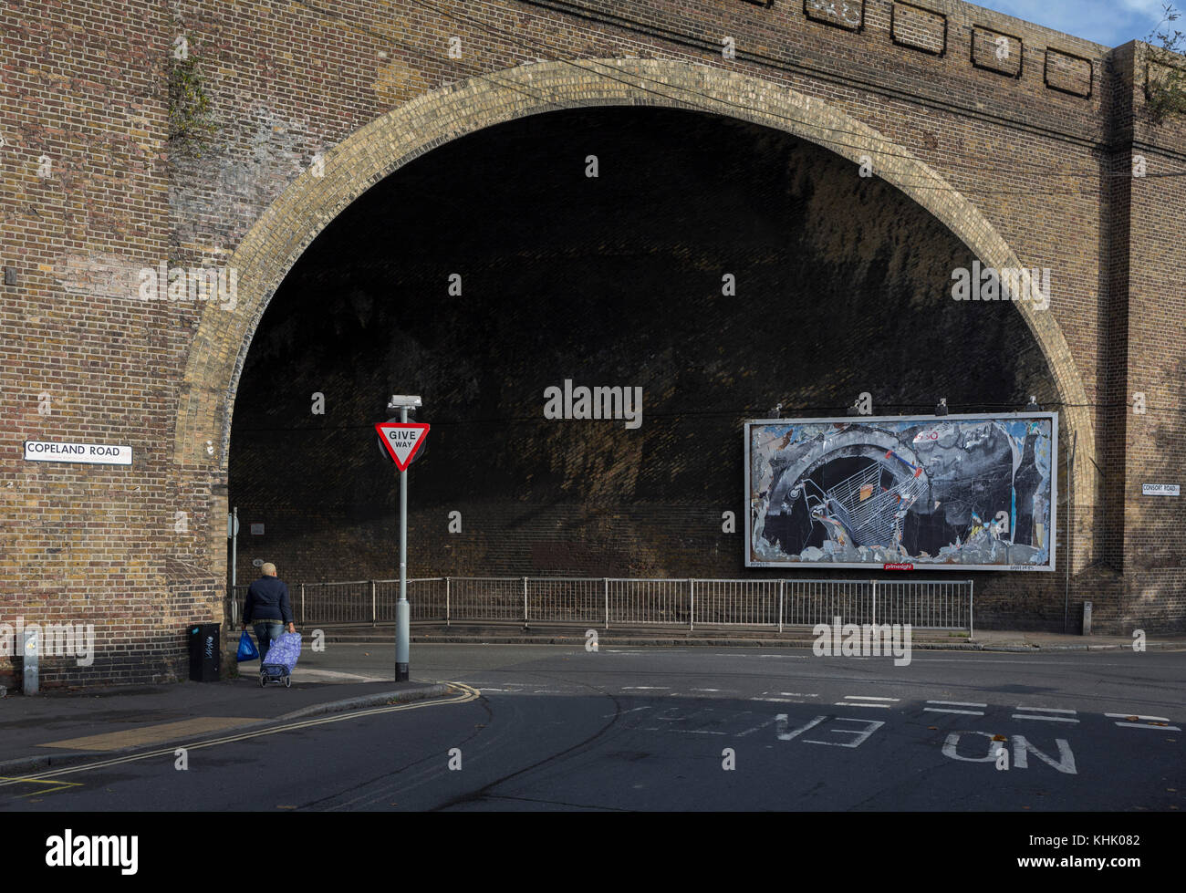 A billboard featuring a a supermarket trolley falling into a drain located beneath the arch of a Victorian-era railway bridge over the road in Peckham, on 16th November 2017, in south London, England. Stock Photo