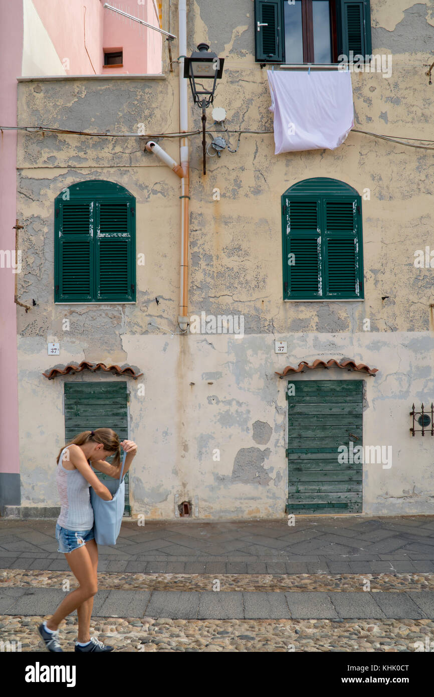 Street scene of narrow houses and washing hanging from a window with a street lamp outside shuttered windows, Sardinia. Stock Photo