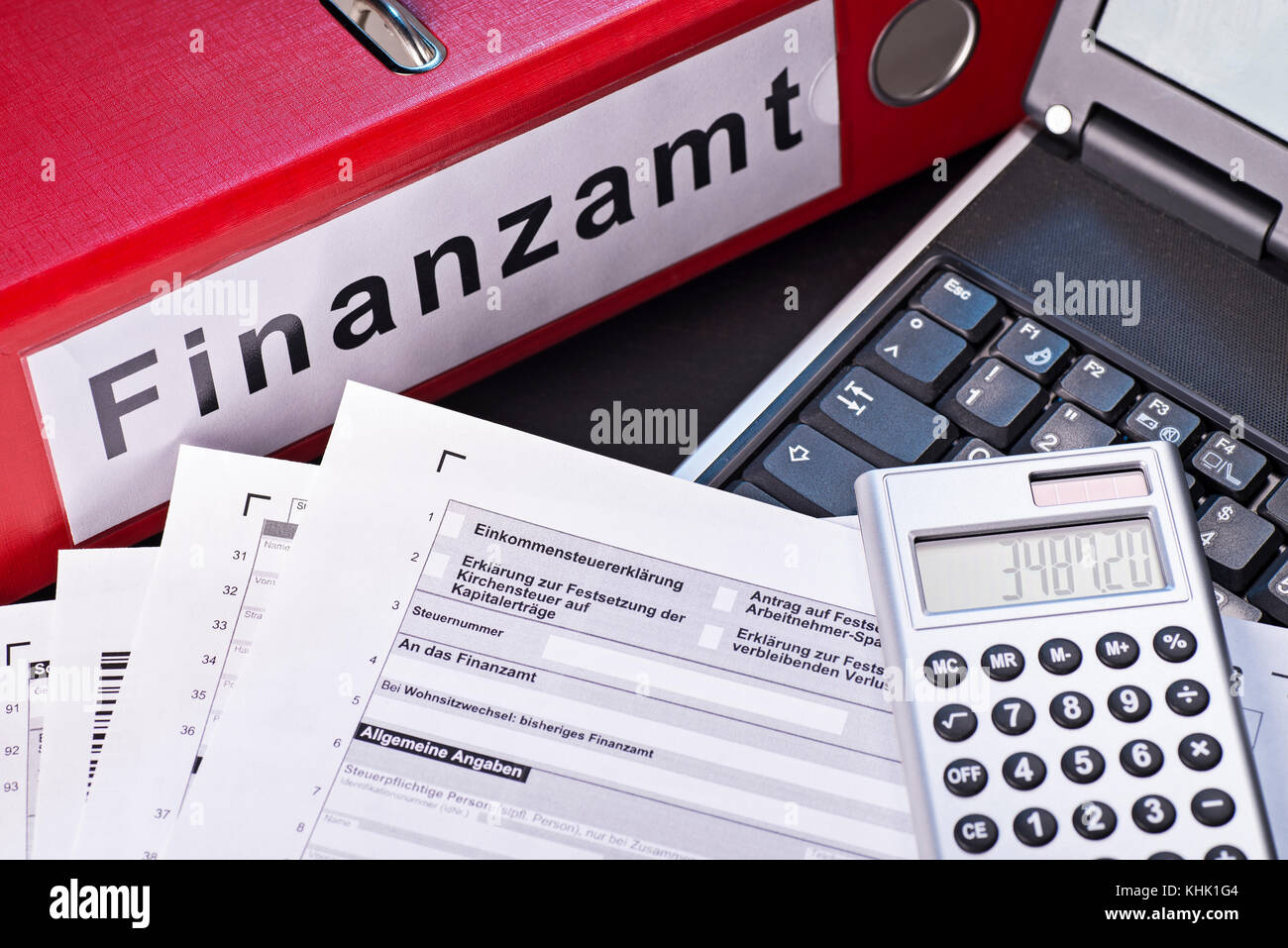 File folder labeled 'Finanzamt' (tax office), forms, calculators and a computer as a symbol for the preparation of the tax return. Stock Photo