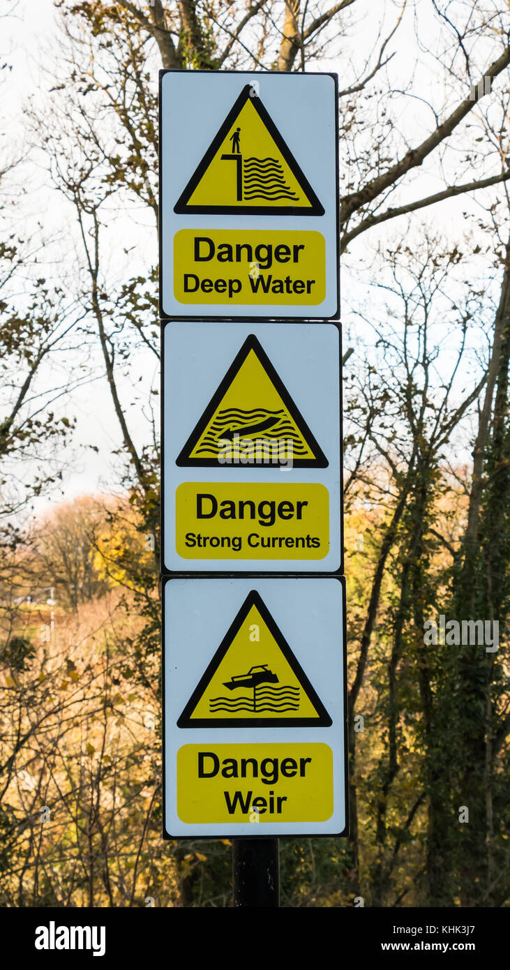 Three signs warning of riverside hazards, deep water, strong currents and a weir on the Tees riverbank at Barnard Castle, North East England, UK Stock Photo