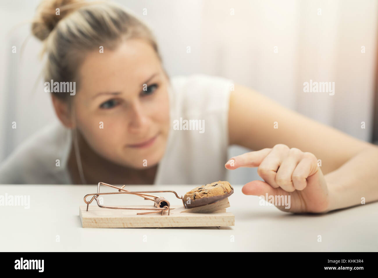 hungry woman trying to steal cookie from mouse trap. weight loss diet plan concept Stock Photo