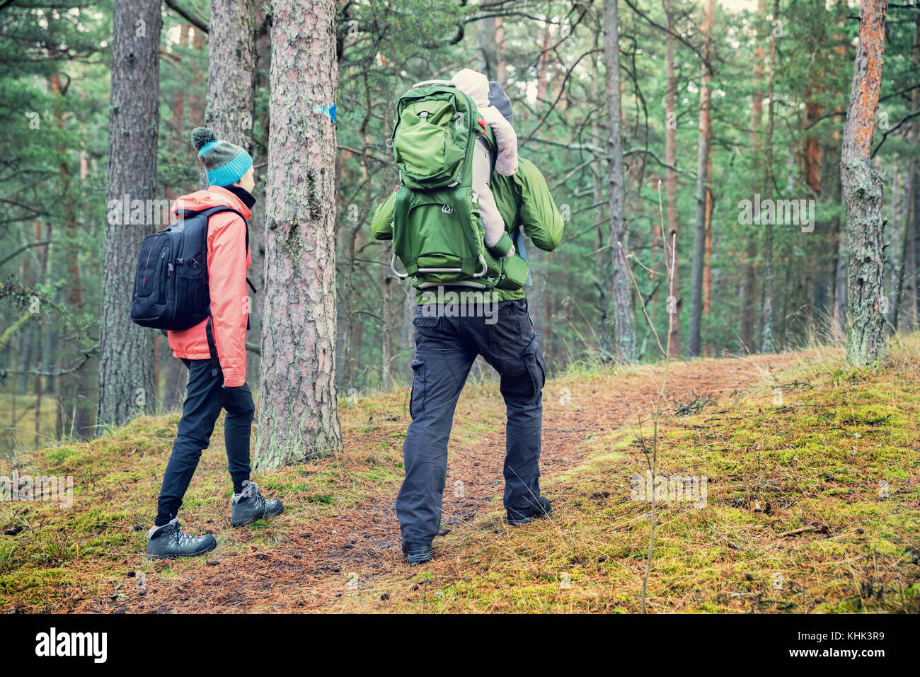 family walking forest trail with baby in child carrier on father's back Stock Photo