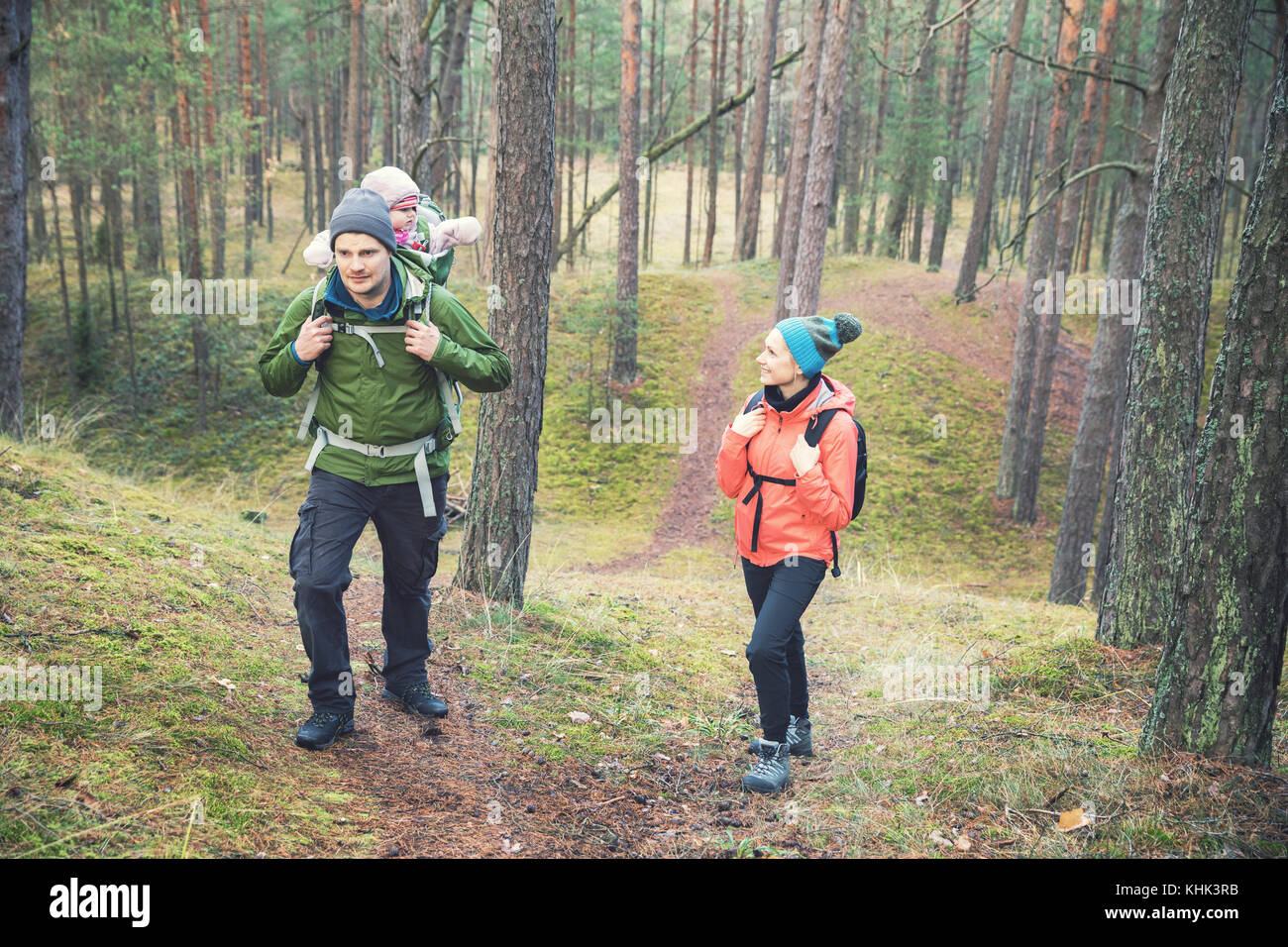 family on a hike in the forest with baby in child carrier on father's back Stock Photo