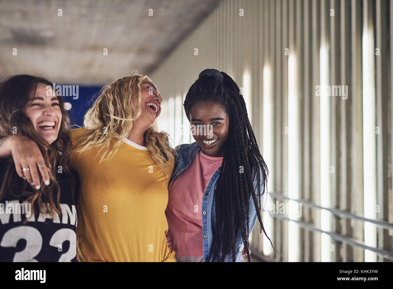Laughing Group Of Diverse Young Female Friends Walking Arm In Arm Together Down A Walkway In The City At Night Stock Photo Alamy