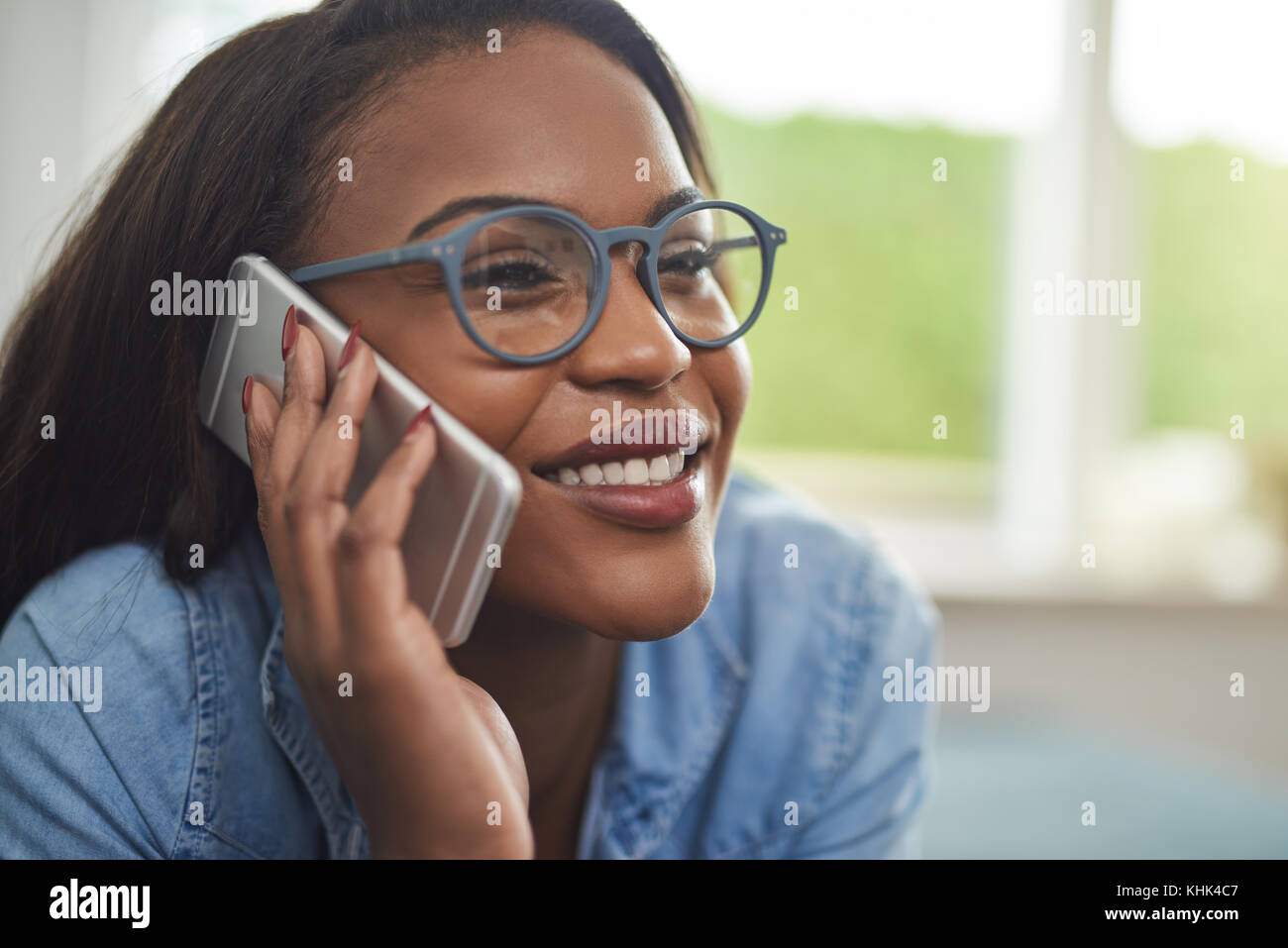 Smiling young African woman wearing glasses lying on the sofa in her ...