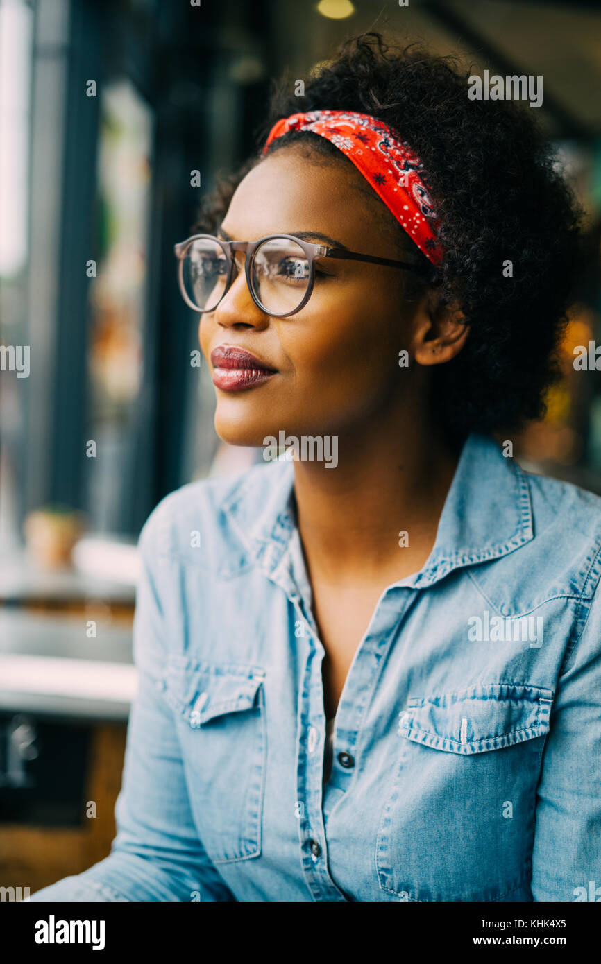 Smiling young African woman wearing glasses and a bandana deep in ...