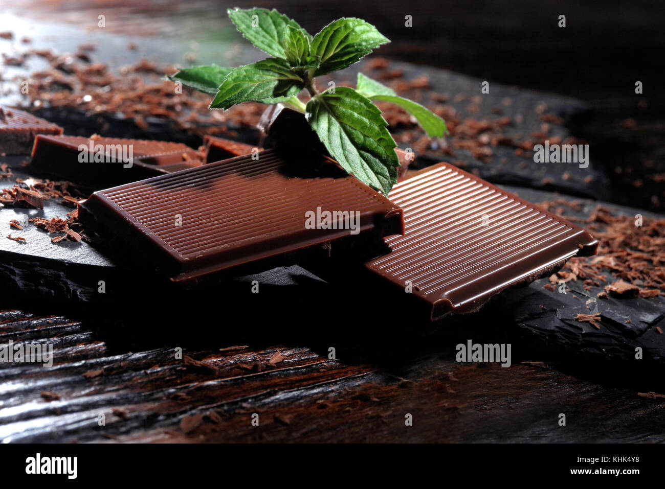 Broken dark chocolate and chocolate flakes on a wooden table Stock Photo