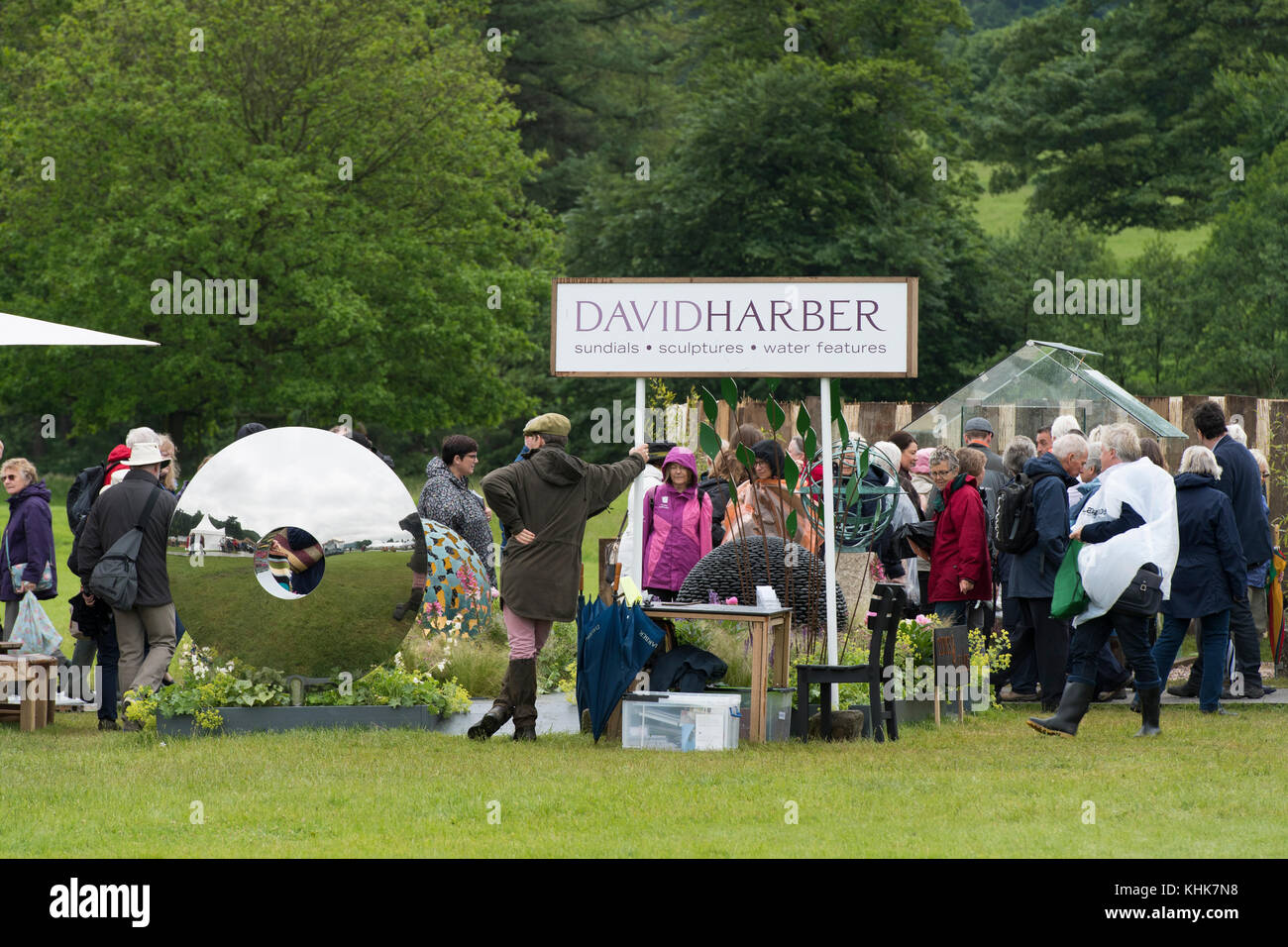 People pass salesman standing by metal sculptures & garden art displayed on trade stand - RHS Chatsworth House Flower Show, Derbyshire, England, UK. Stock Photo