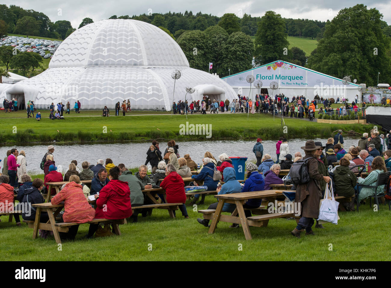 Large crowd at RHS Chatsworth Flower Show - sitting at picnic tables, & going into large white marquees - Chatsworth House, Derbyshire, England, UK. Stock Photo