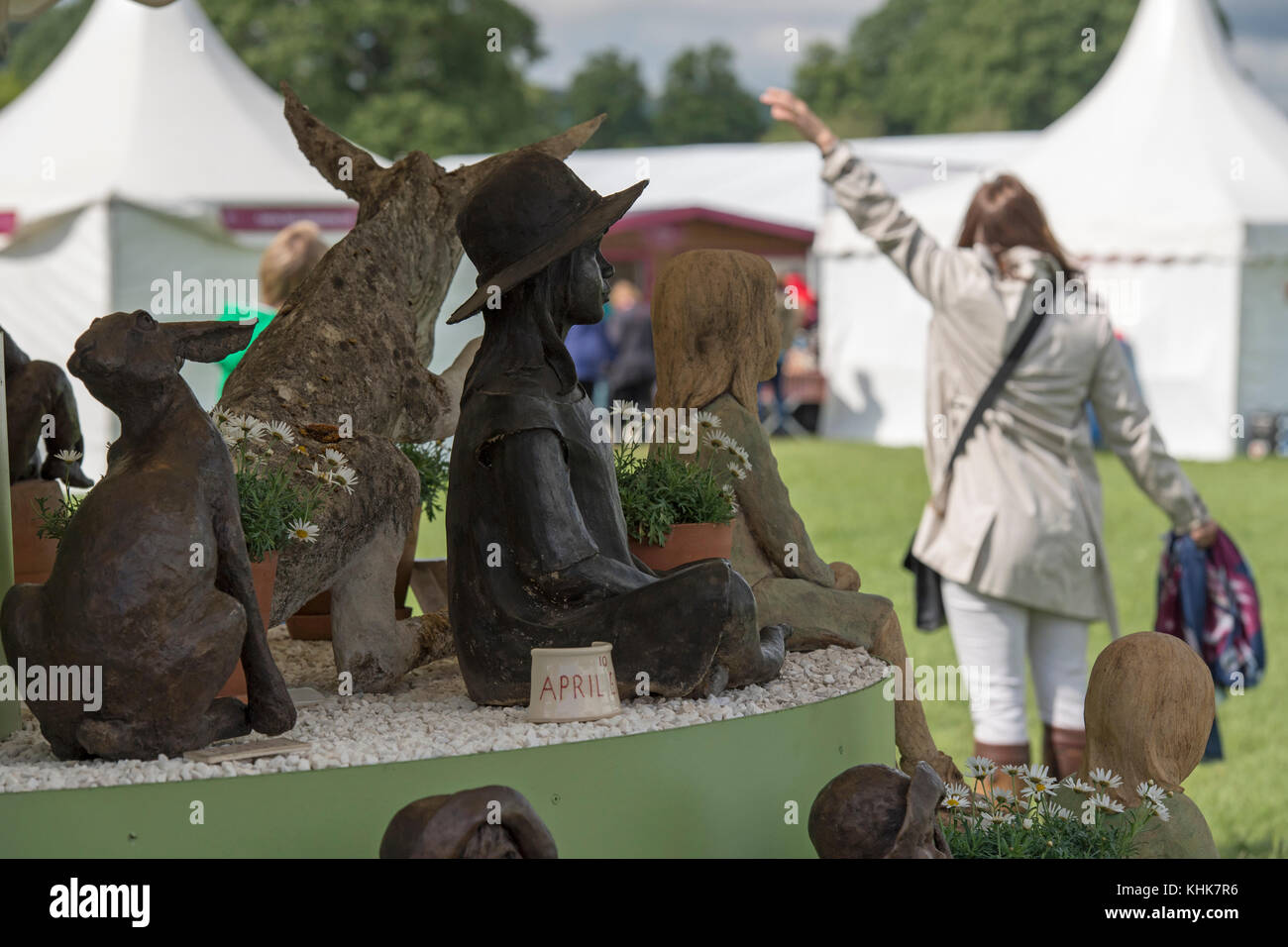 Close-up of figurative sculptures on Ann Hogben trade stand with one woman beyond - RHS Chatsworth Flower show showground, Derbyshire, England, UK. Stock Photo