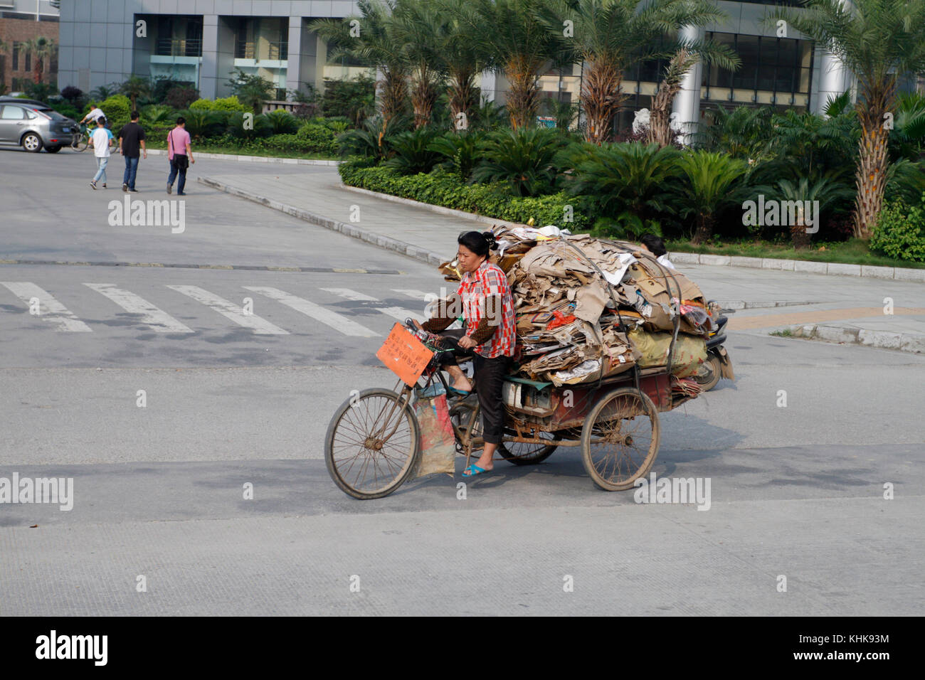 A woman peddling a pedicab with a heavy load in Guilin, China. Stock Photo