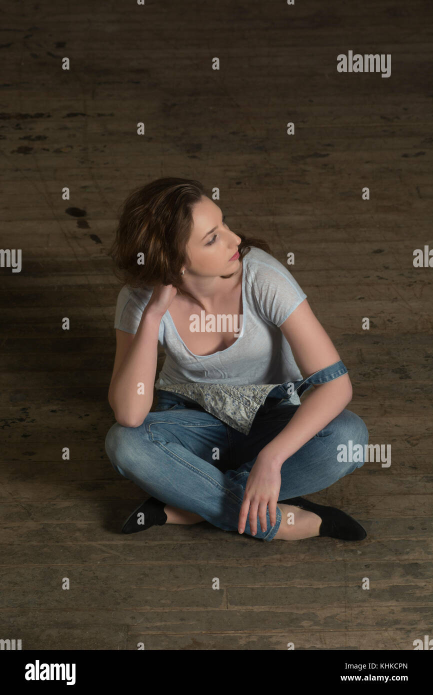 Beautiful young woman sitting on the floor looking away Stock Photo - Alamy