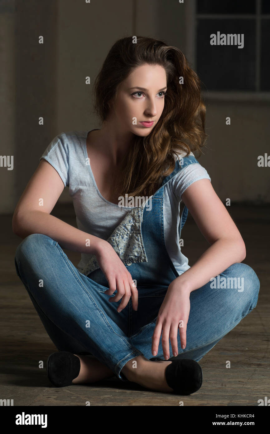 Beautiful young woman sat on the floor looking away Stock Photo - Alamy