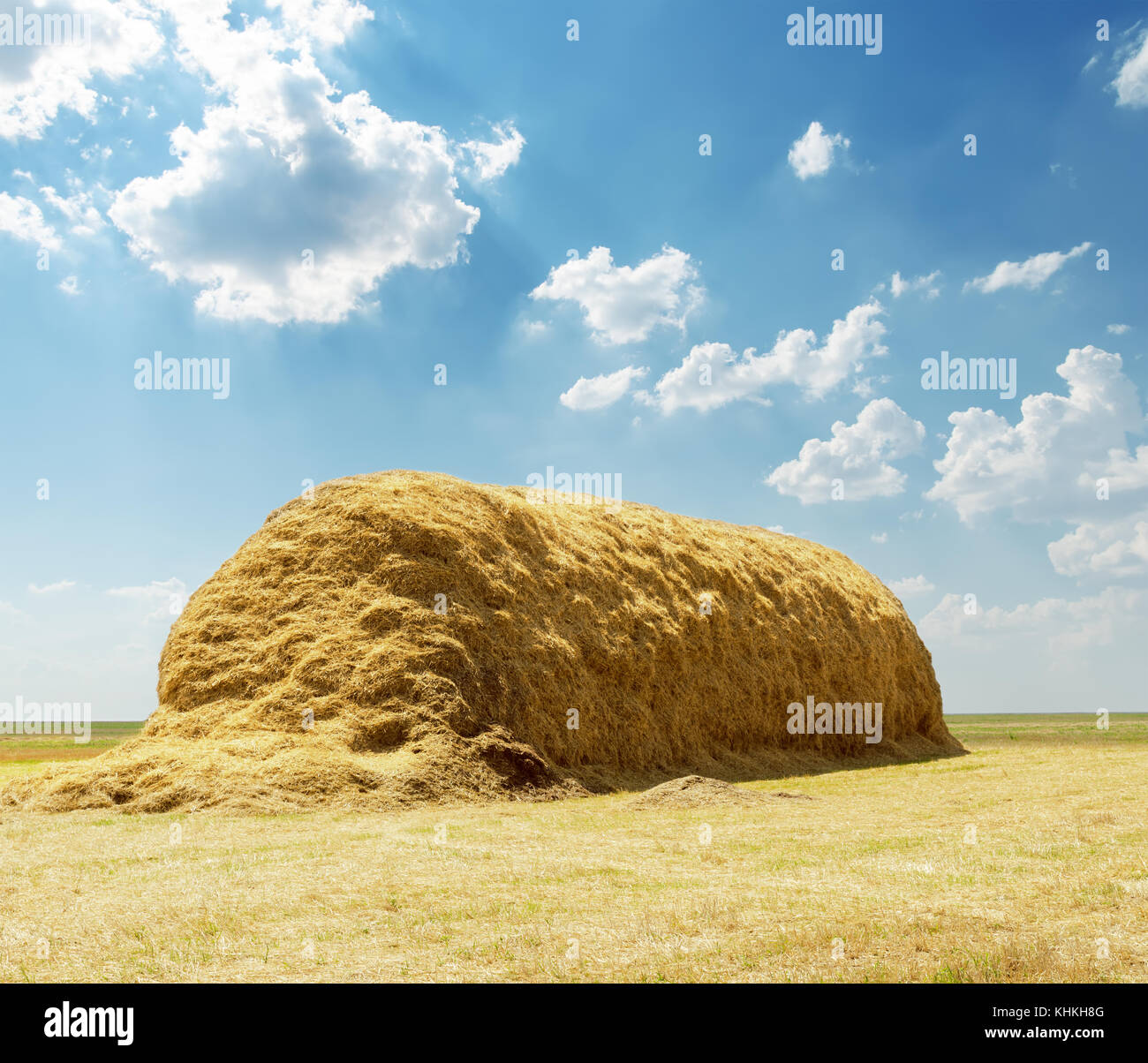 stack of straw under blue sky with clouds Stock Photo - Alamy