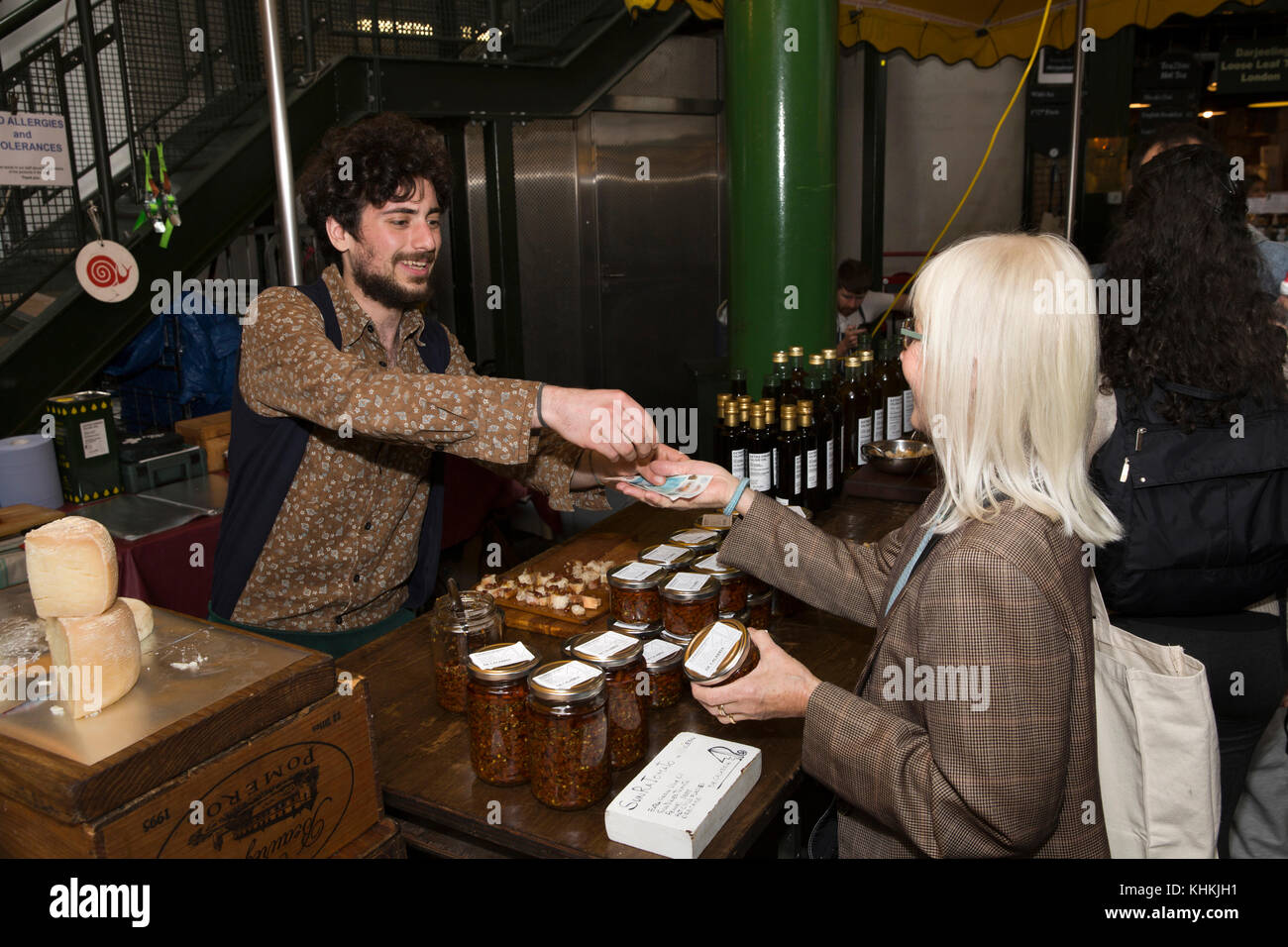 UK, London, Southwark, Borough Market, Three Crown Square, customer buying jar of sun dried tomatoes with chilli Stock Photo