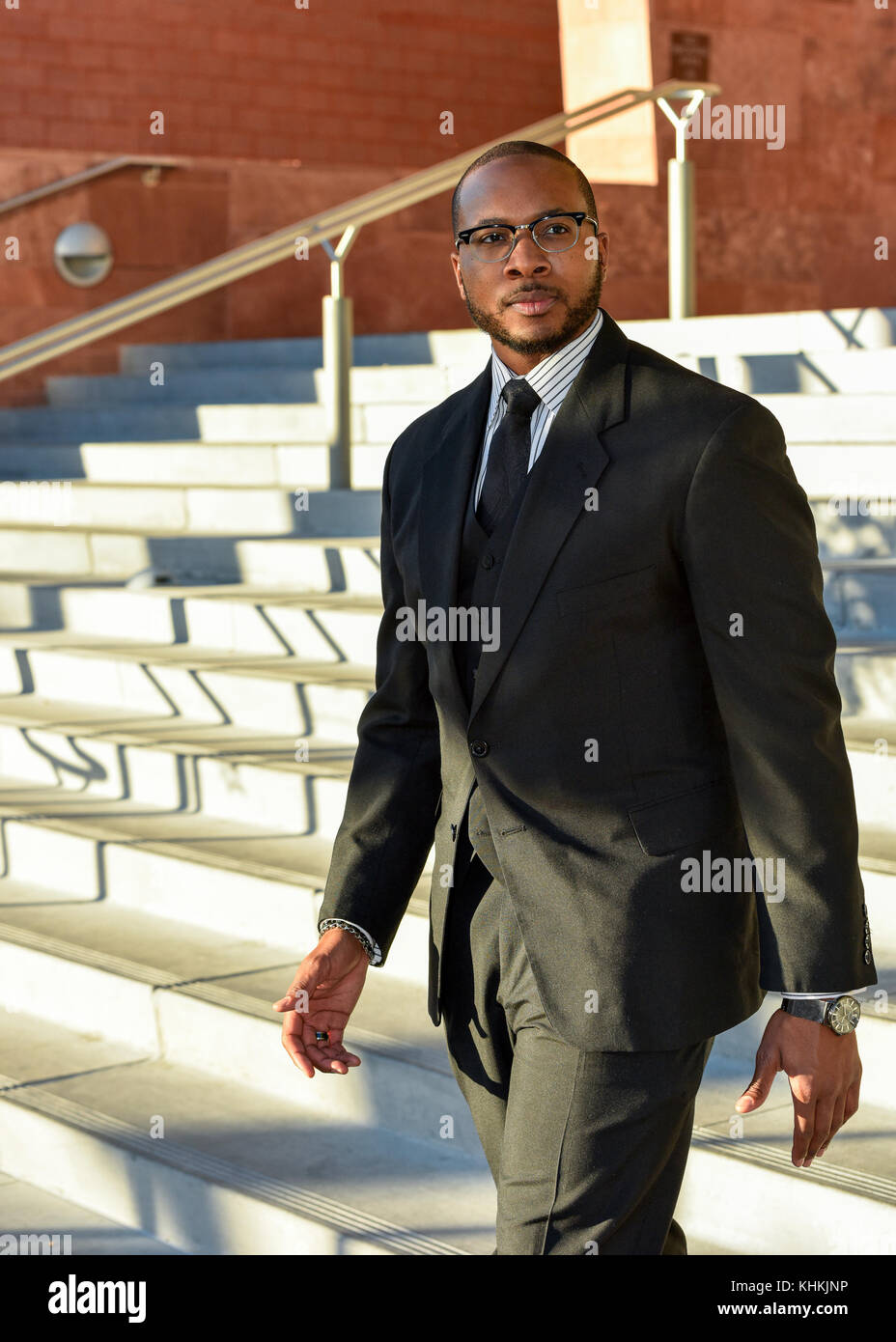 Black American businessman walking down steps in front of a downtown business. Stock Photo