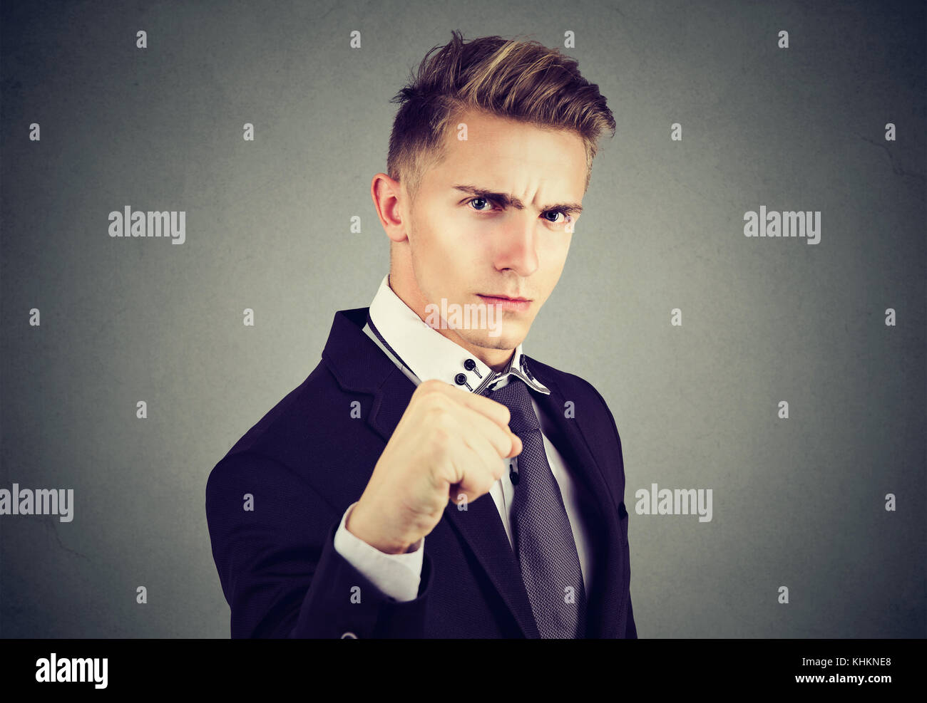 Angry business man with closed fist looking at camera on gray background Stock Photo