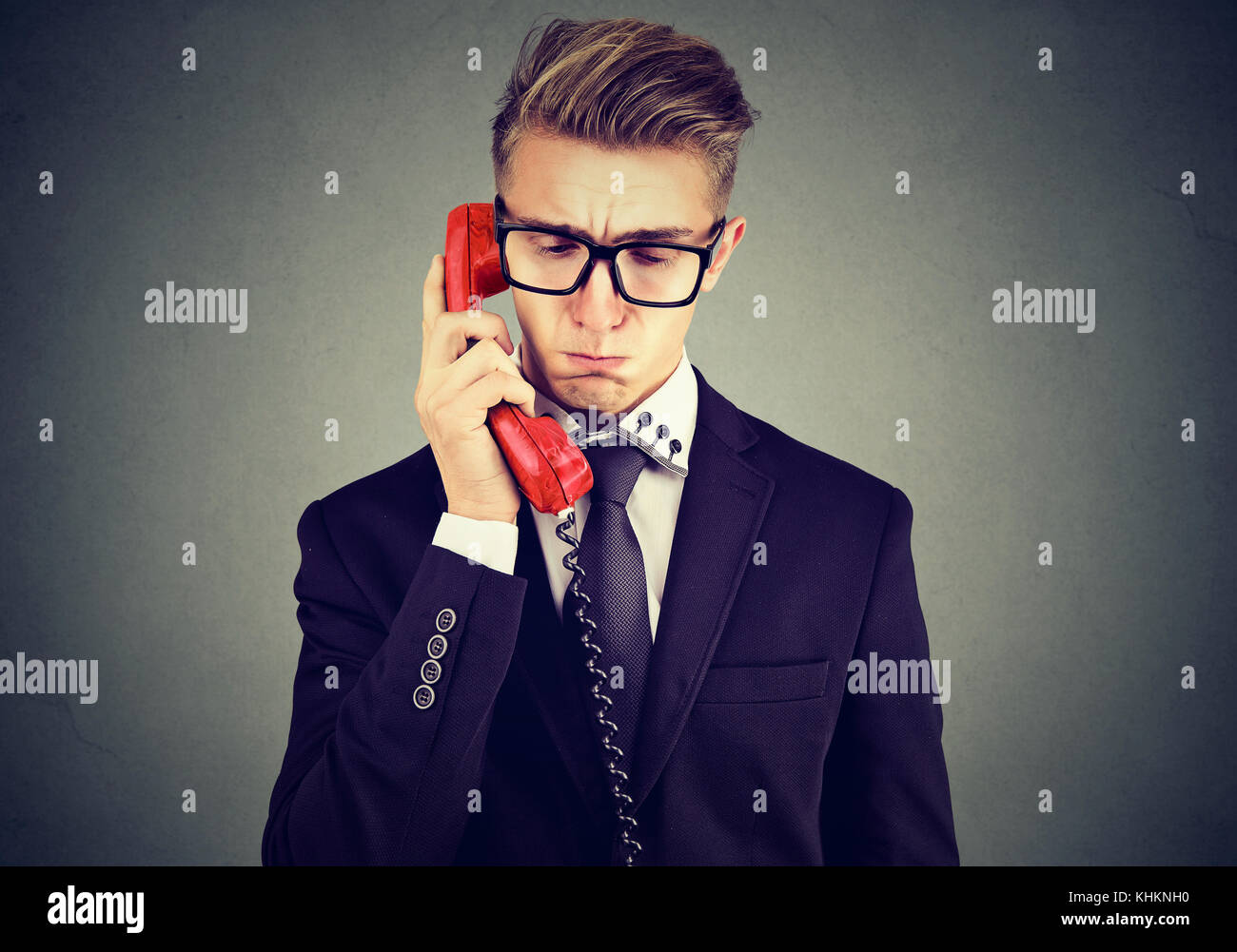 Sad handsome young man having unpleasant telephone conversation looking down Stock Photo