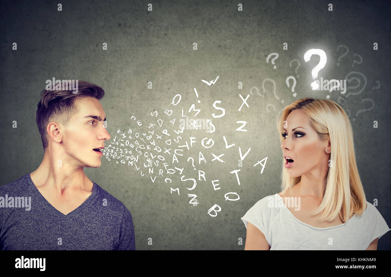 Language barrier concept. Handsome man talking to an attractive young woman with question mark Stock Photo