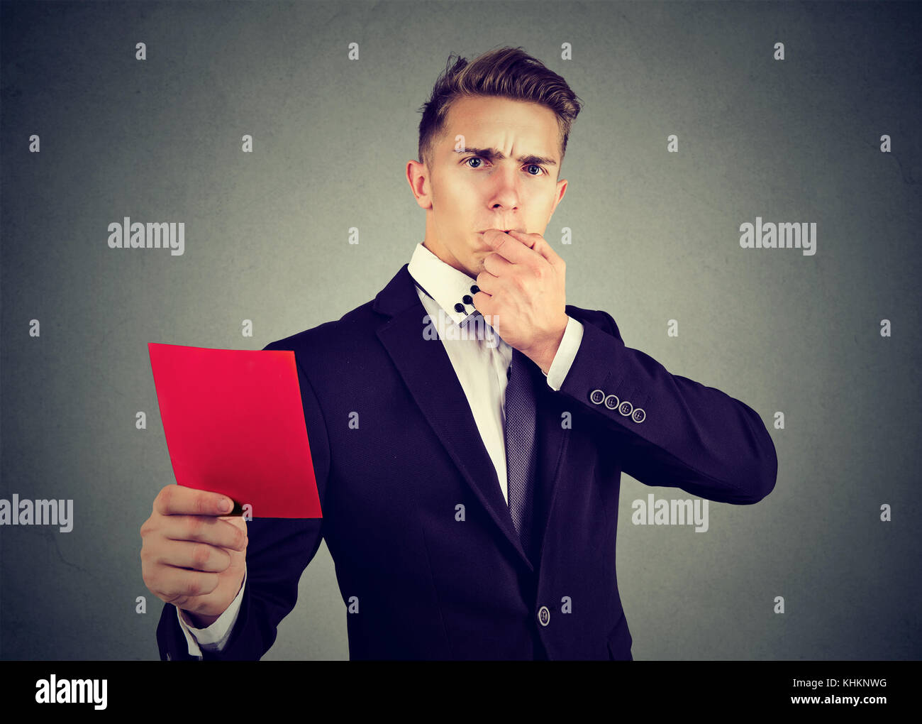 Young frustrated business man referee whistling and showing a red card Stock Photo