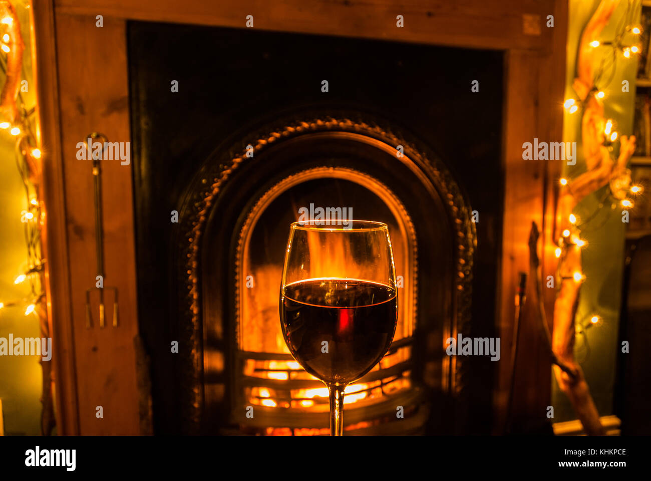 A glass of red wine beside an open fire. Stock Photo