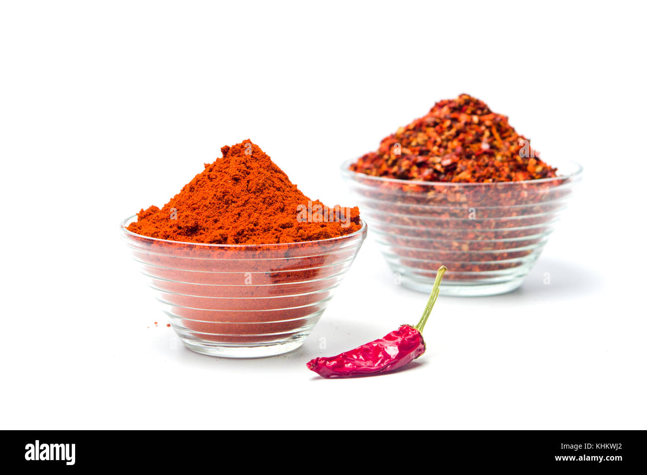 Smashed and ground red pepper powder in a glass bowl isolated Stock