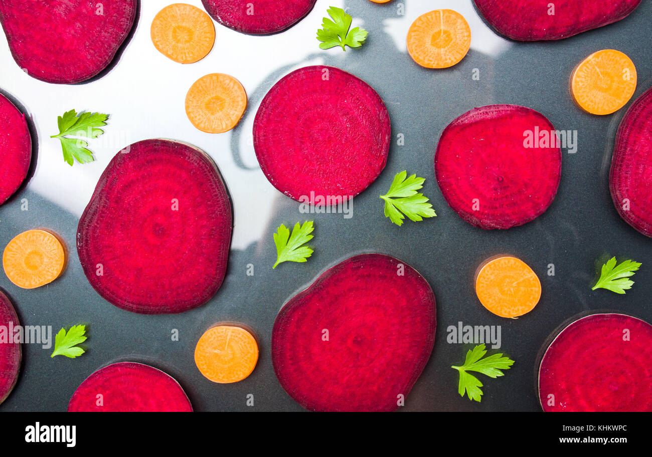 Raw beet and carrot slices isolated on dark background Stock Photo