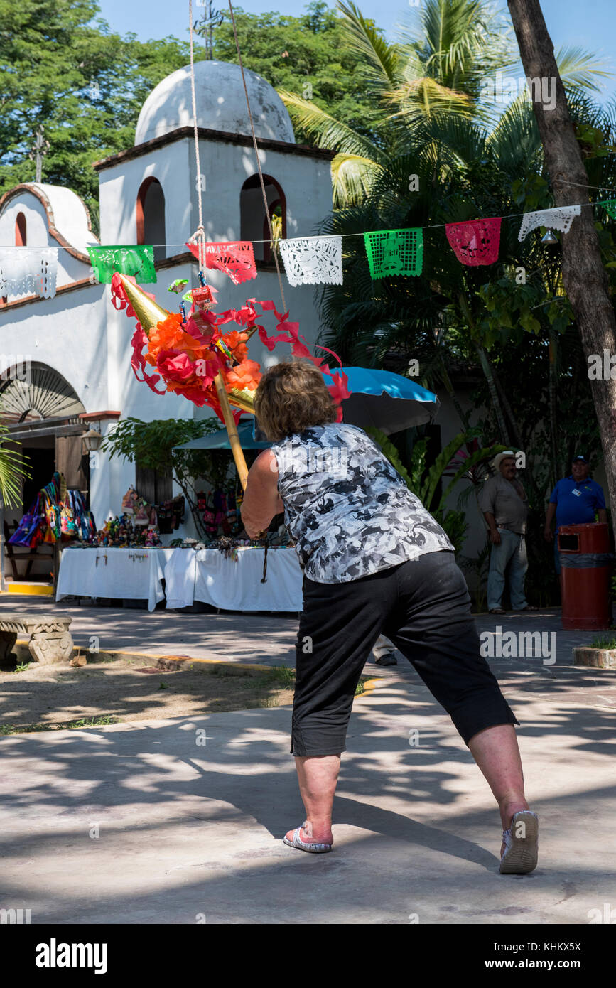 Mexico, State of Jalisco, Puerto Vallarta, Hacienda Dona Engracia. Tourist  breaking traditional pinata with stick to break open and release the candy  Stock Photo - Alamy