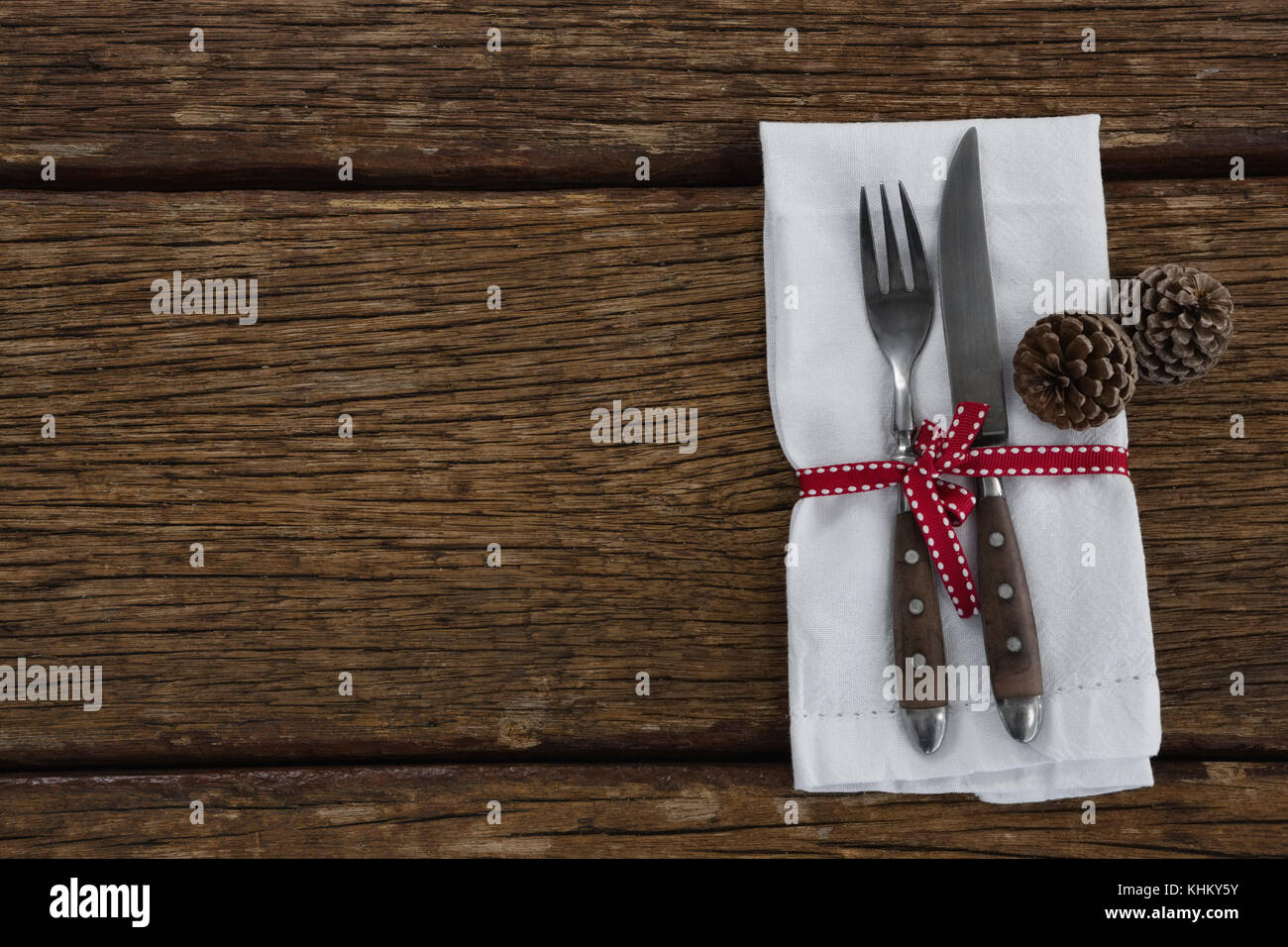 Overhead view of pine cone with fork, butter knife and napkin tied up ...