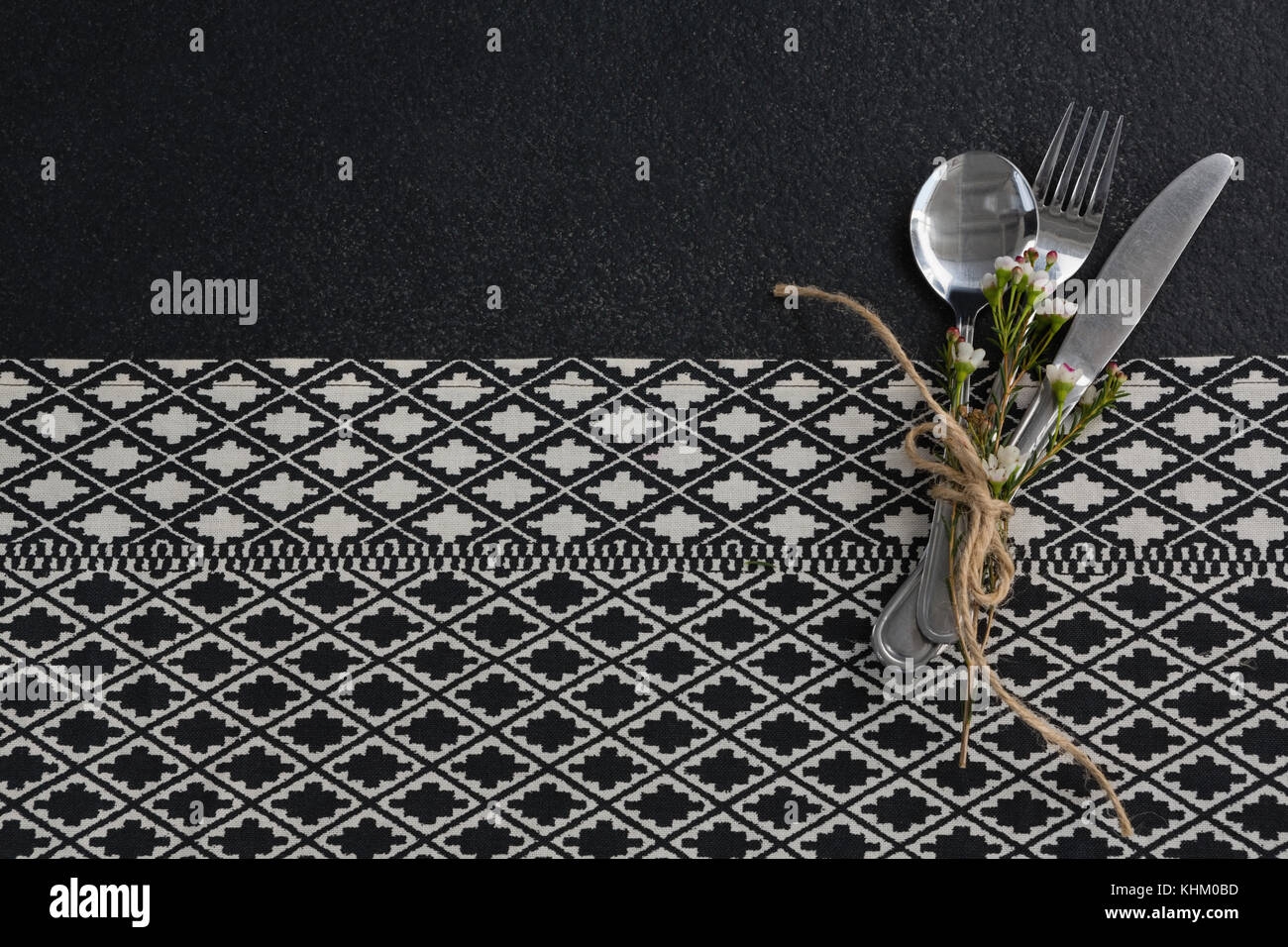 Spoon, fork, butter knife and flower tied up with rope on table cloth