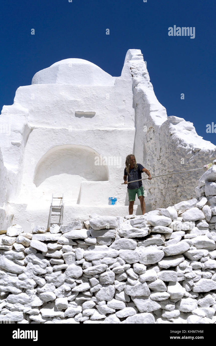 Worker painting Panagia-Paraportiani church with white lime paint, Mykonos-town, Mykonos island, Cyclades, Aegean, Greece Stock Photo