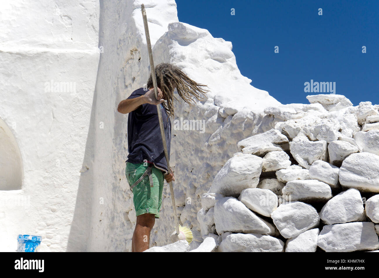 Worker painting Panagia-Paraportiani church with white lime paint, Mykonos-town, Mykonos island, Cyclades, Aegean, Greece Stock Photo