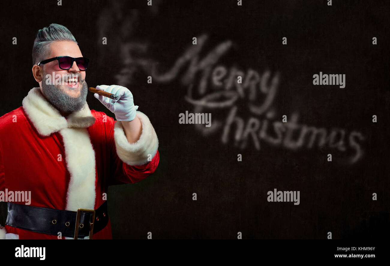 Santa Claus with a cigar launches a smoke with the text of Merry Stock Photo