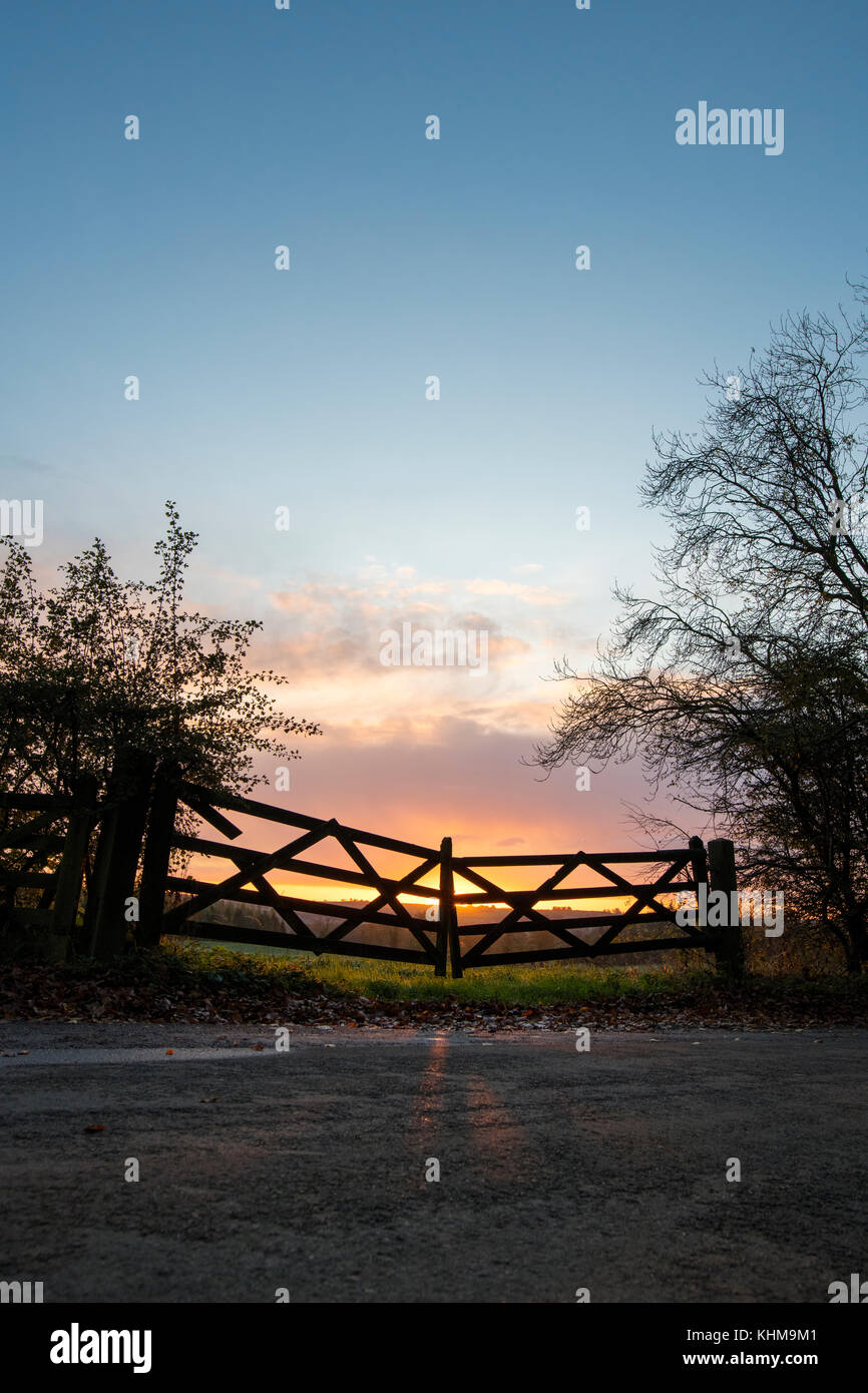 Silhouette farm gates at sunrise on an autumn morning in the english countryside. Cotswolds, Oxfordshire, England Stock Photo