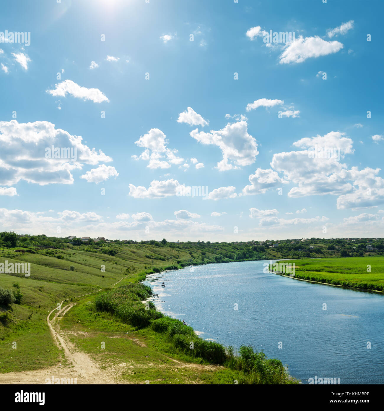 sun in blue sky with clouds over river Stock Photo - Alamy