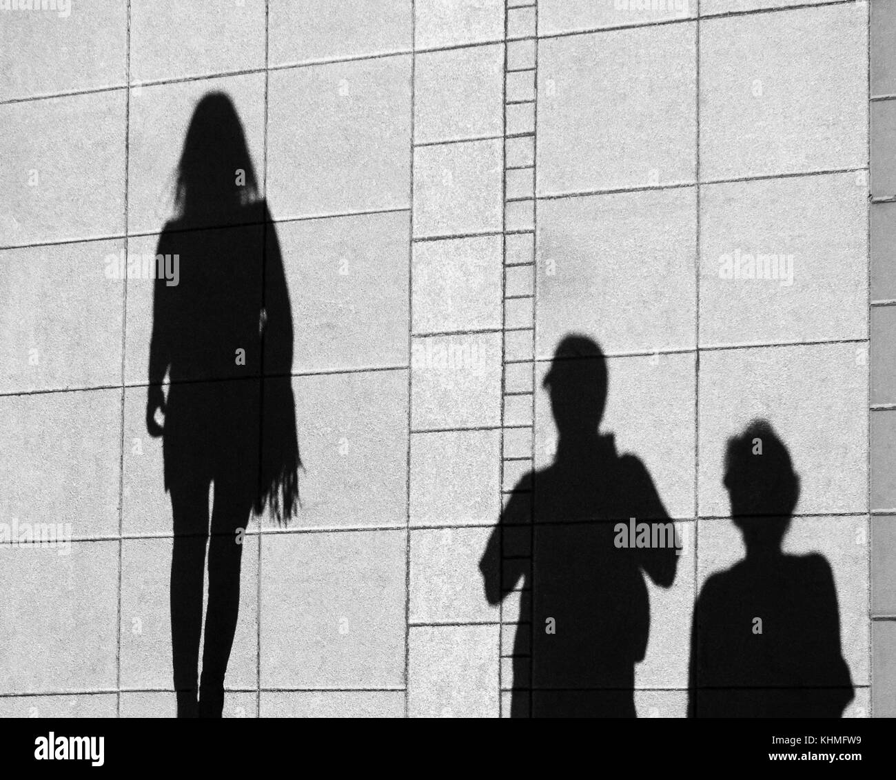 Shadow of parents and teenage daughter , on city sidewalk from above Stock Photo