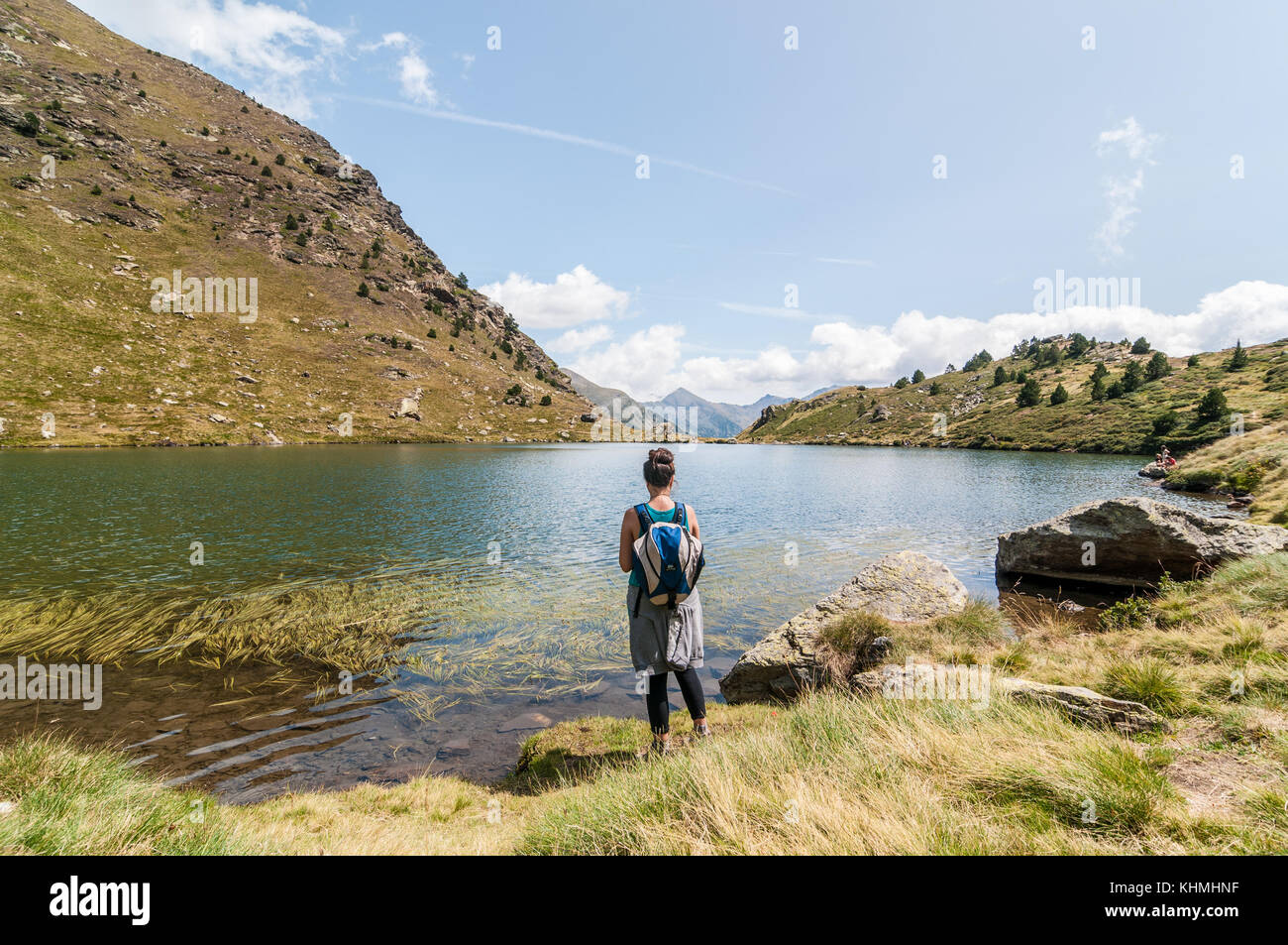 view of high mountain lake called 'Estany primer' near Ordino with a woman from behind in the foreground, Tristaina, Andorra Stock Photo