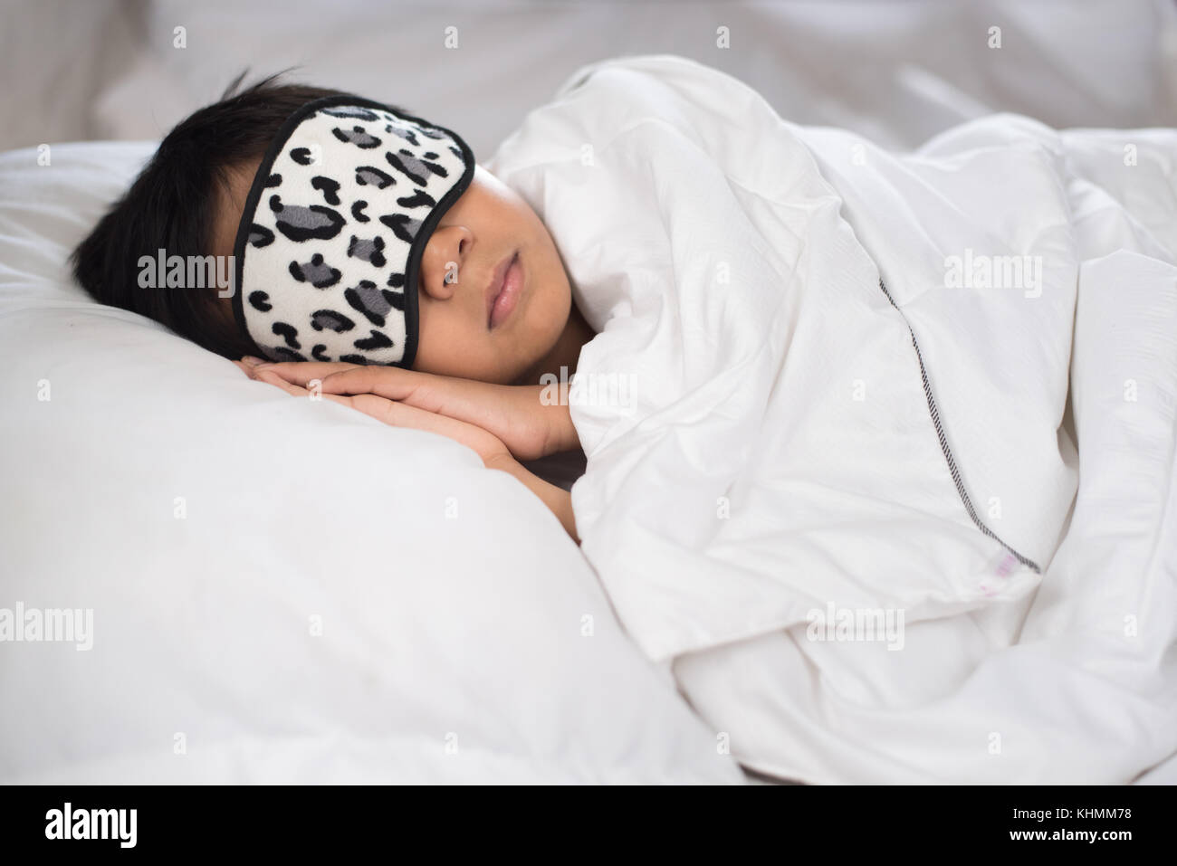 boy sleeping on bed white pillow and sheets with sleep mask.boy