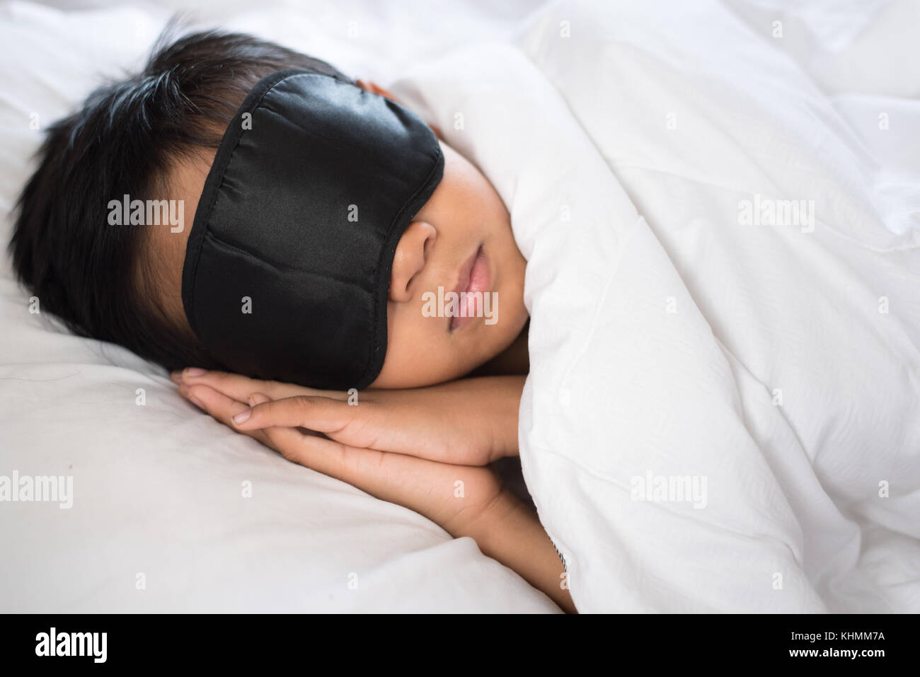 boy sleeping on bed white pillow and sheets with sleep mask.boy