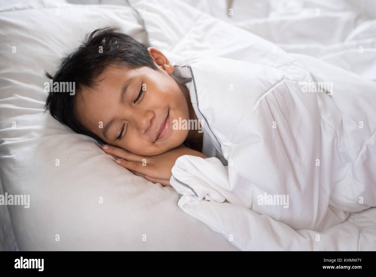 Boy Sleeping With Smile Face On White Bed Sheet And Pillow Boy