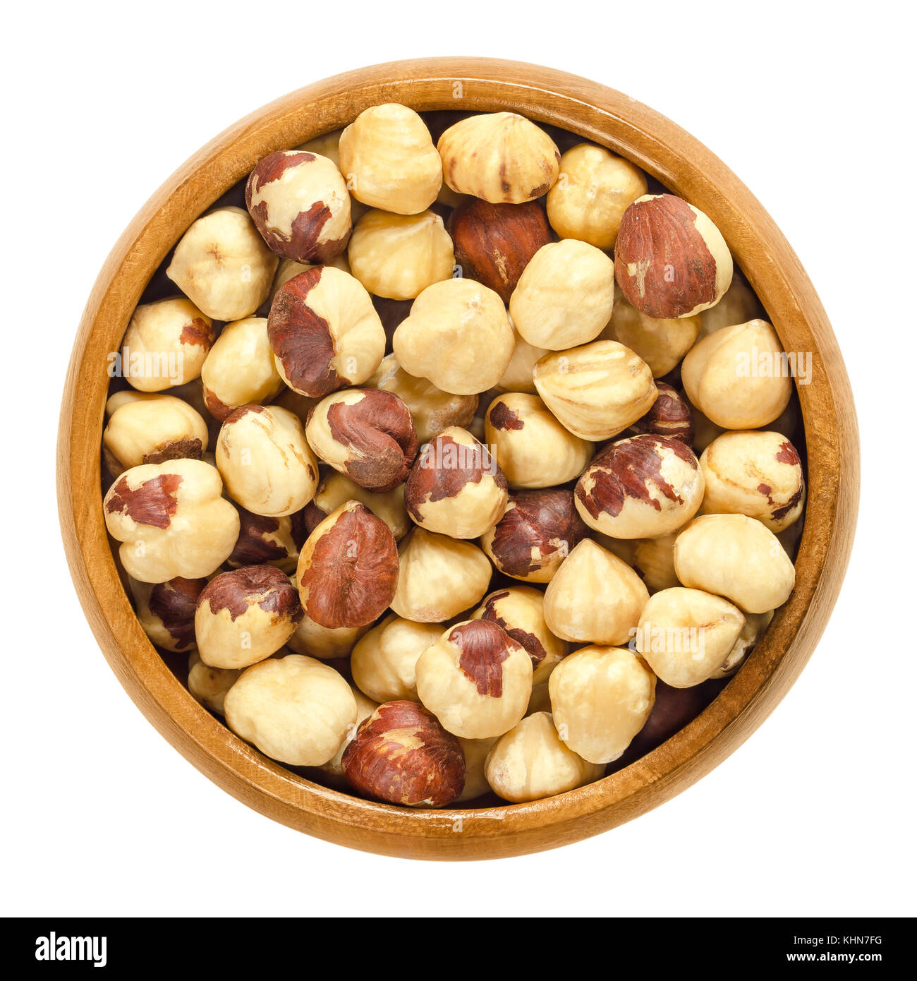 Roasted hazelnuts in wooden bowl. Crisp toasted nuts of the hazel. Shelled whole seeds of cobnuts or filbert nuts, Corylus avellana. Macro food photo. Stock Photo
