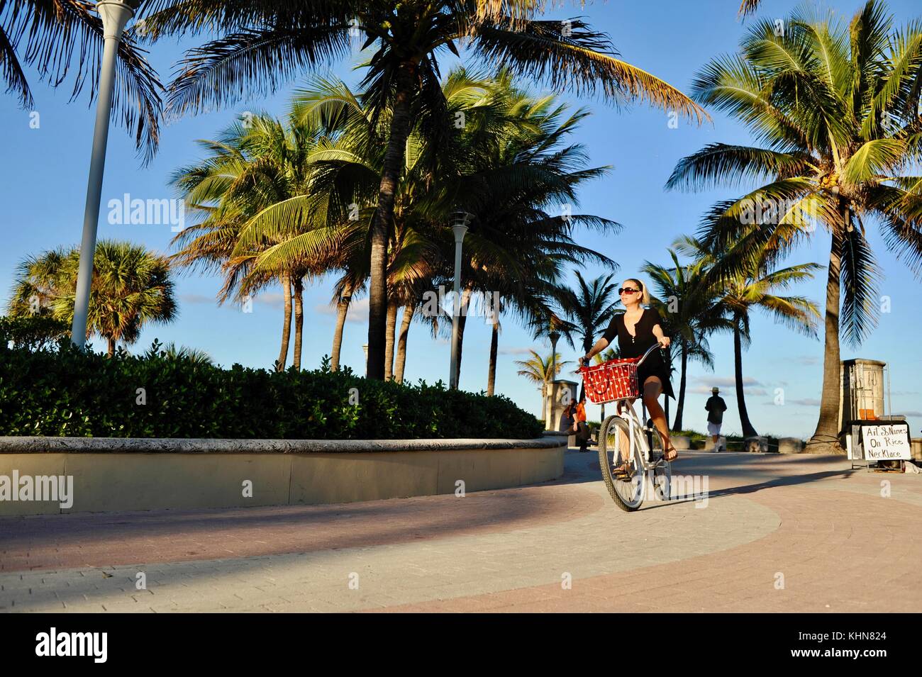 Woman in dress bicycling along Serpentine Pathway in South Beach, Miami, Florida, USA. Stock Photo